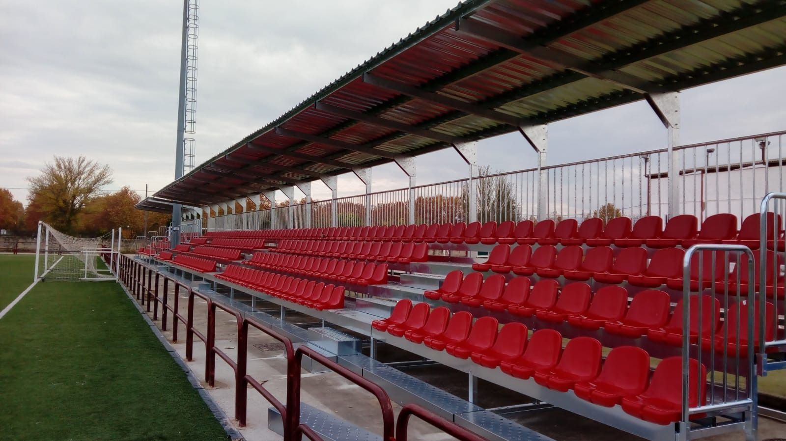 Una fila de asientos rojos en un estadio en un campo de fútbol.