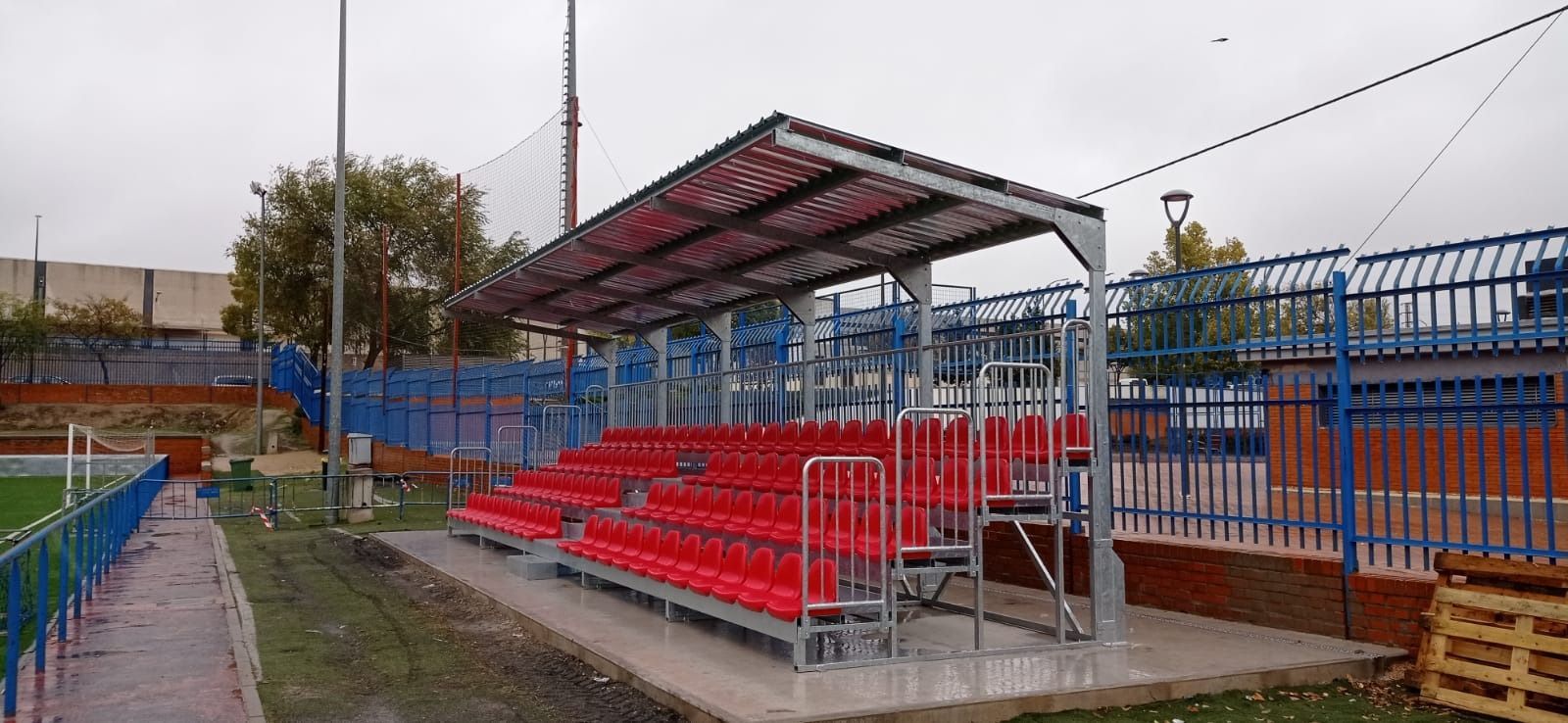 Un estadio con asientos rojos y una valla azul.