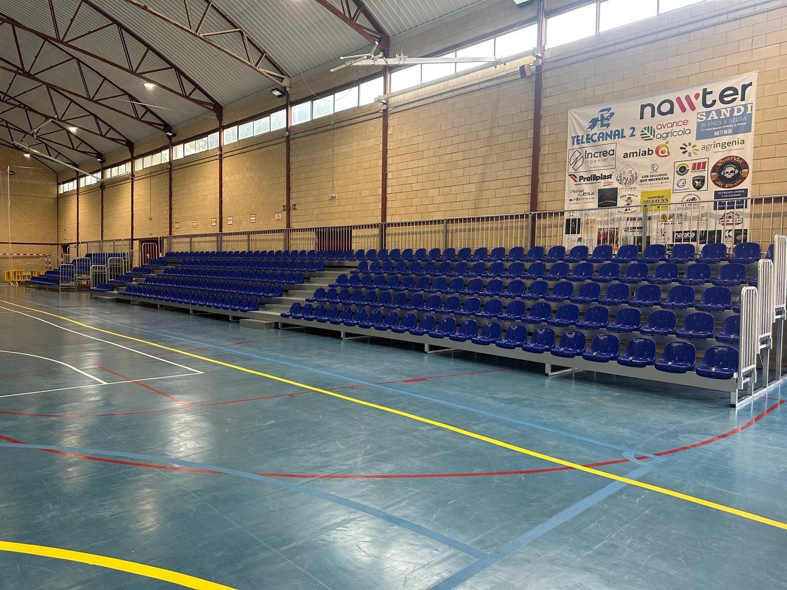 Un gran estadio cubierto con asientos azules y un cartel en la pared.