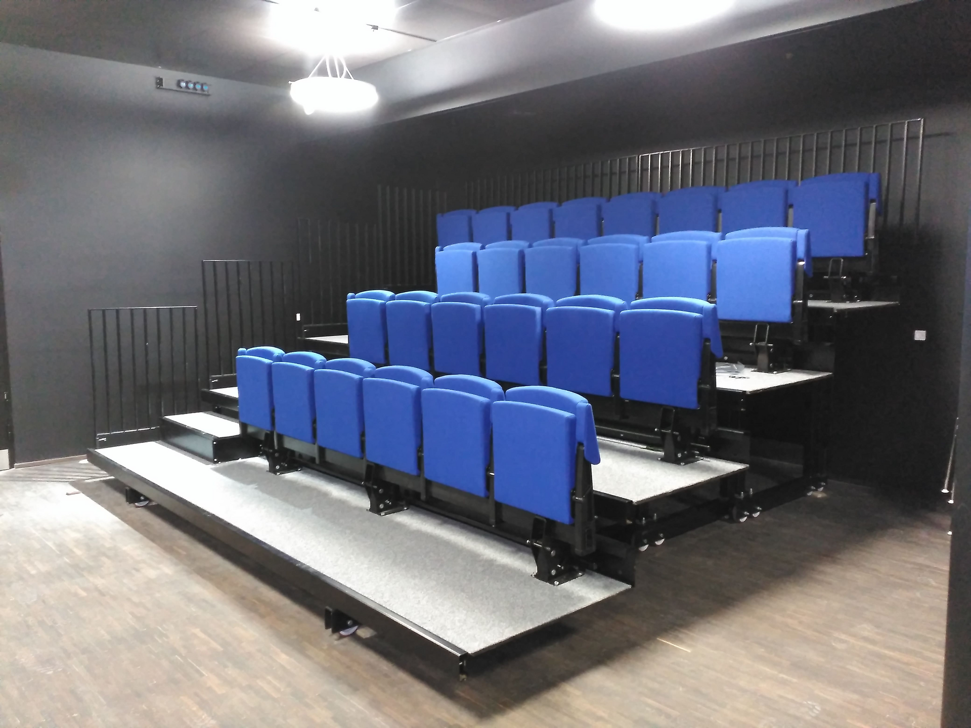 Una fila de asientos azules en un auditorio oscuro