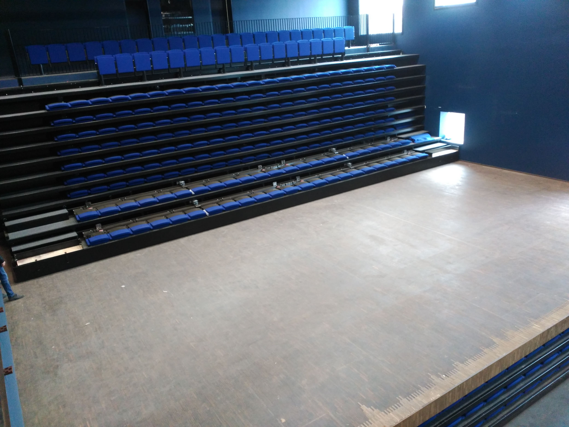 Un auditorio vacío con asientos azules y un escenario.