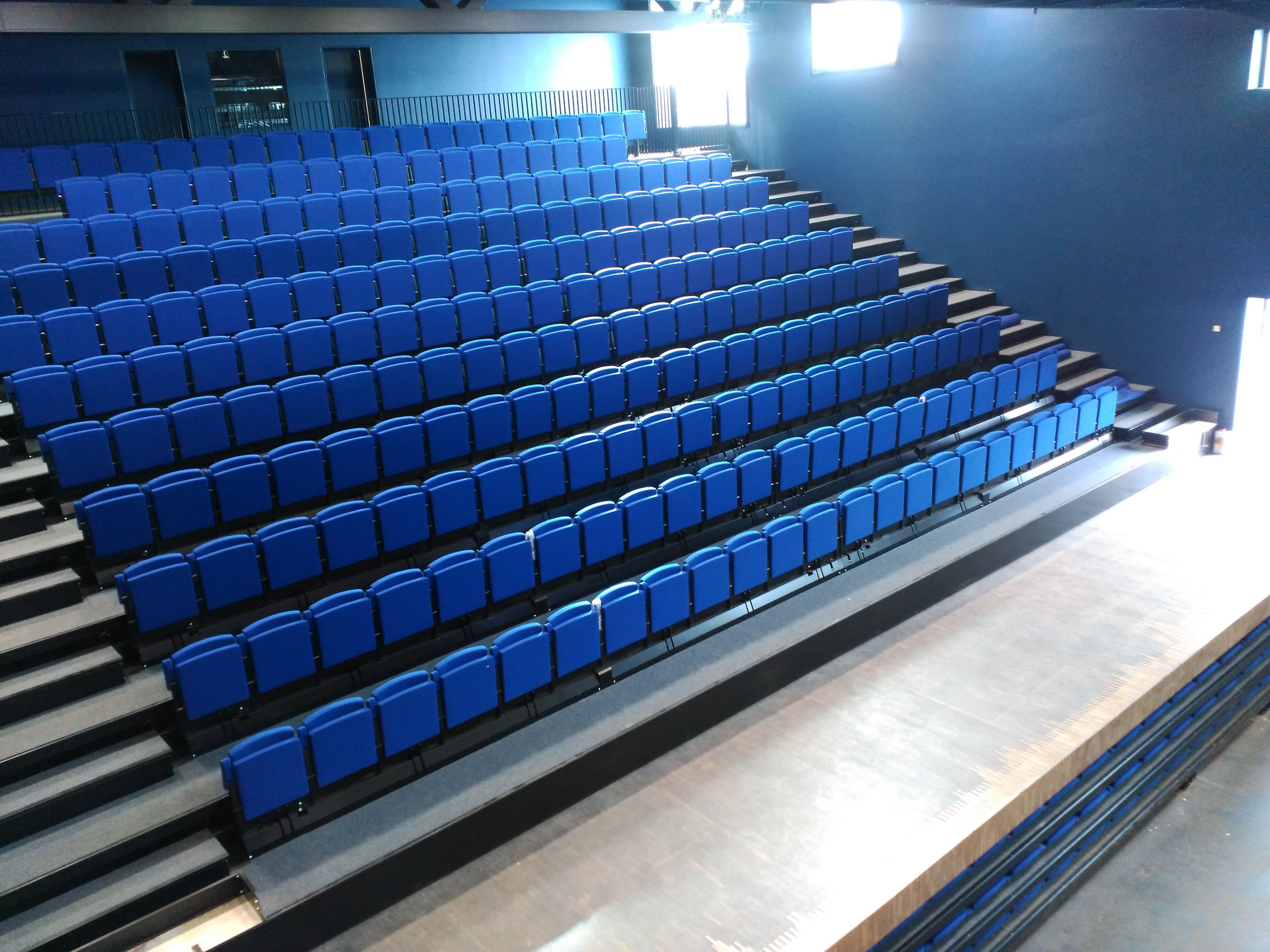 Filas de asientos azules en un auditorio con escaleras