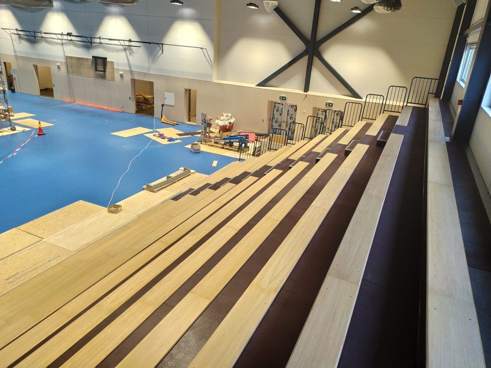 Un estadio con gradas de madera y suelo azul.