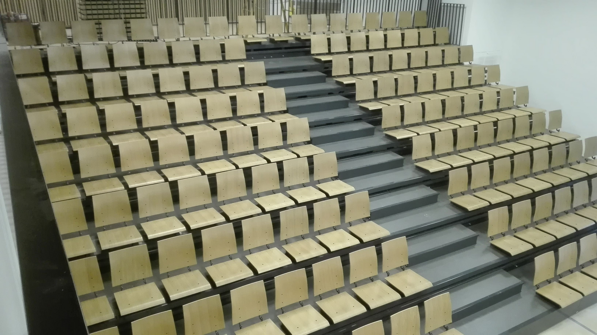 Una fila de asientos de madera en un auditorio con escaleras.