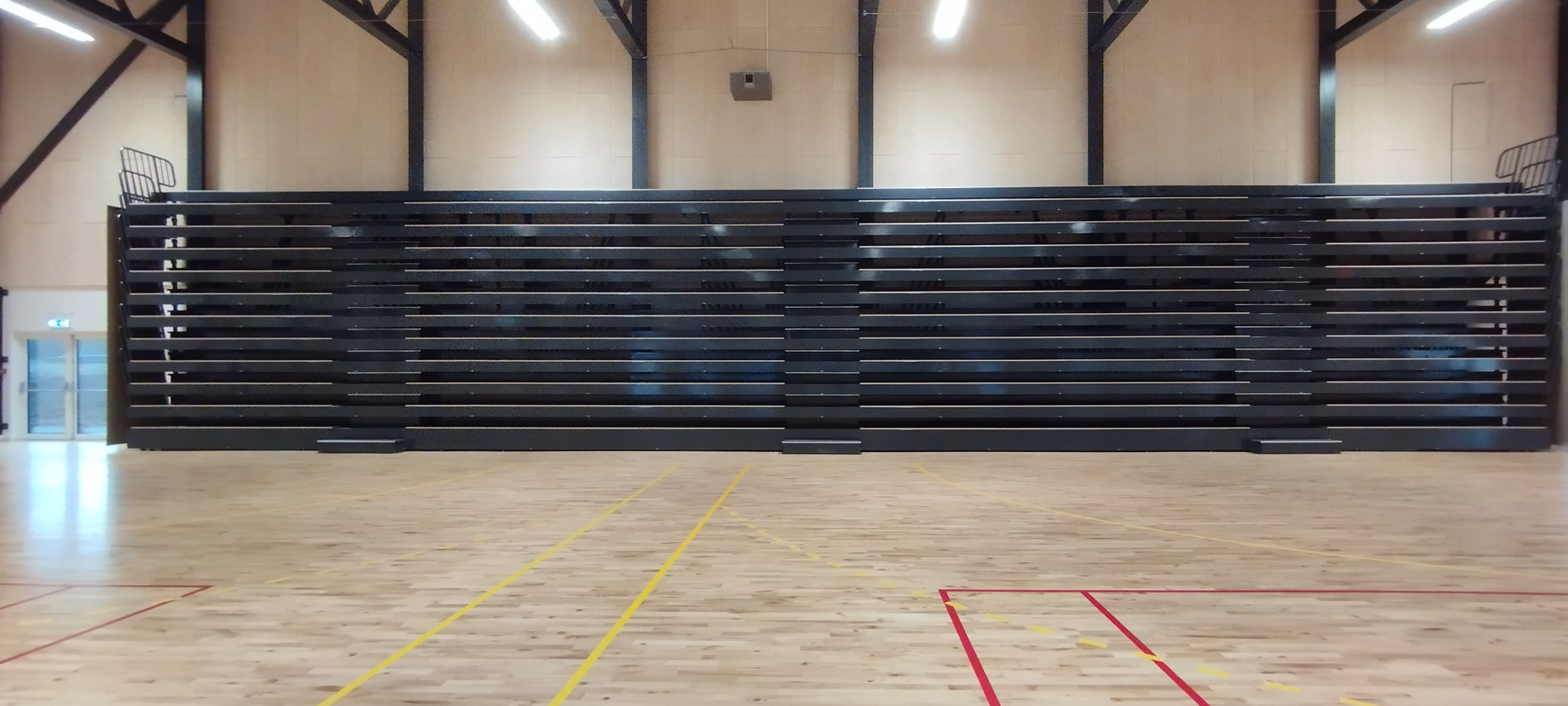 Un gran gimnasio vacío con suelo de madera y gradas.