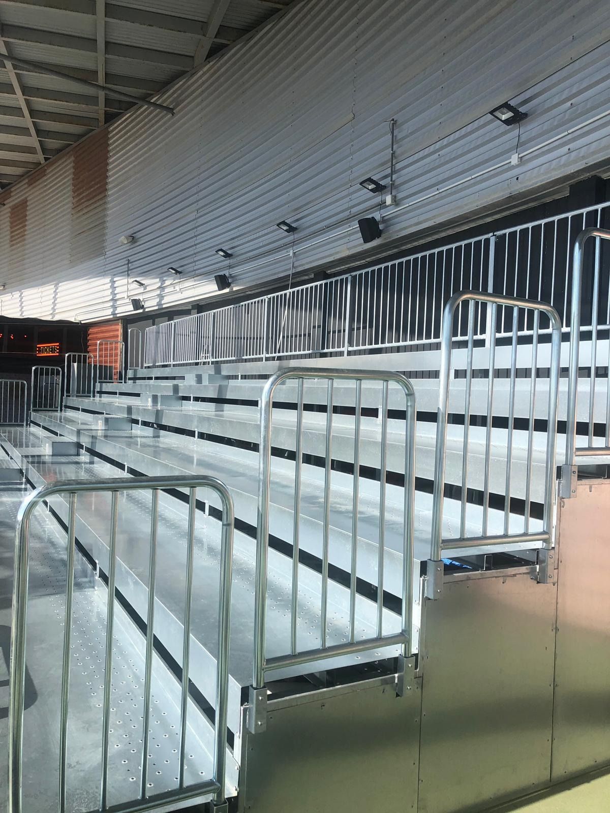 Una fila de gradas con barandilla de metal en un estadio.