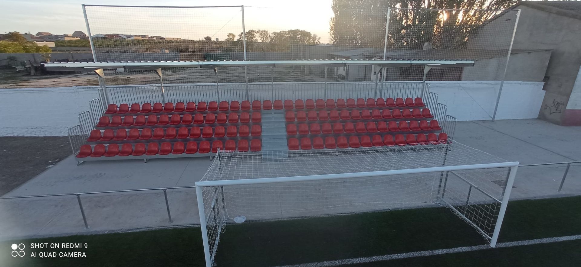 Una vista aérea de un campo de fútbol con asientos rojos y una portería.