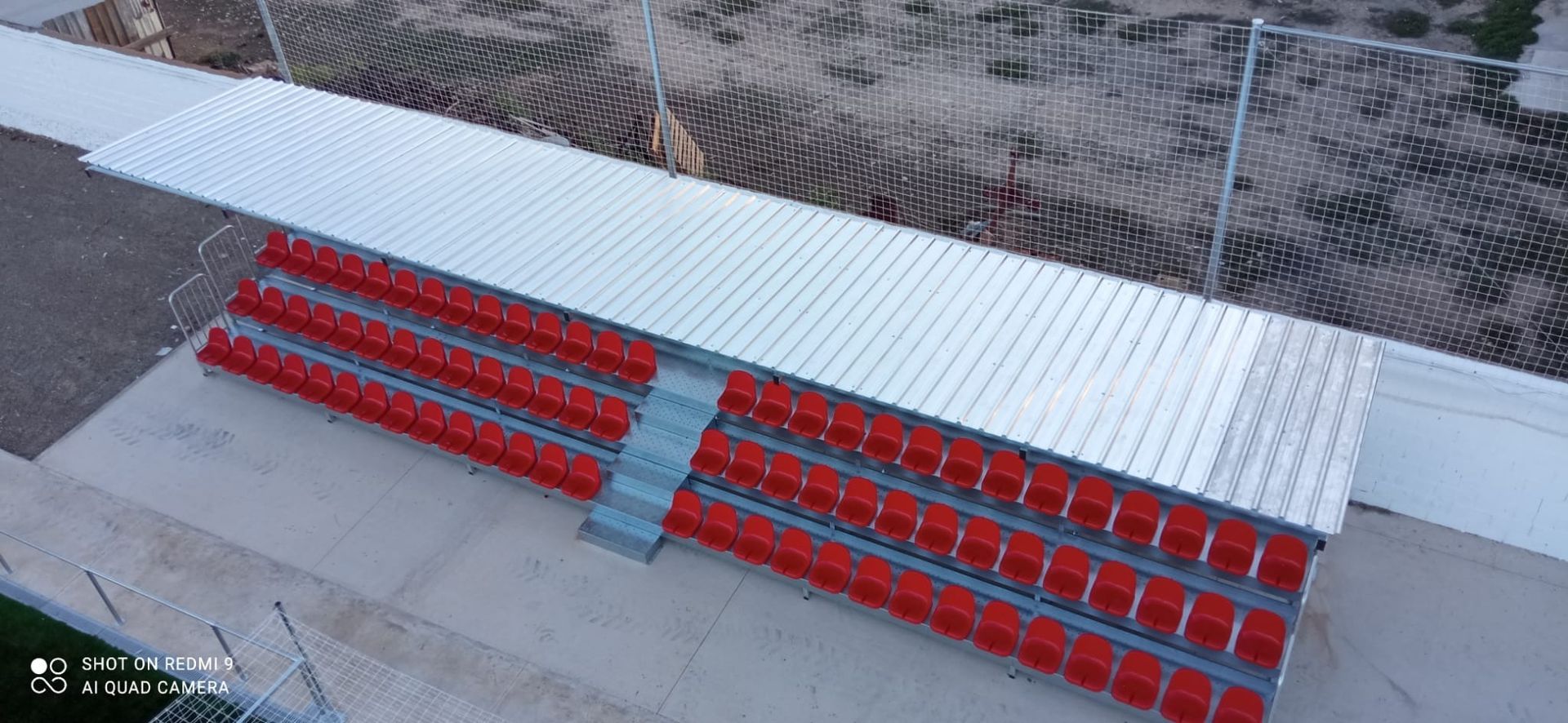 Una vista aérea de un estadio con asientos rojos y techo blanco.