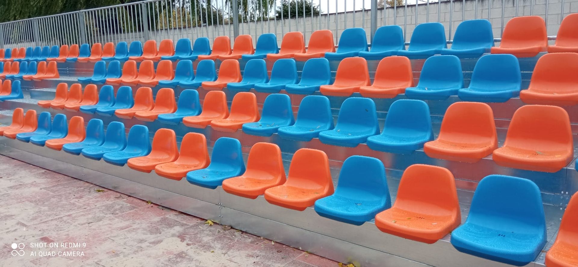 Una fila de asientos de plástico azul y naranja en un estadio.