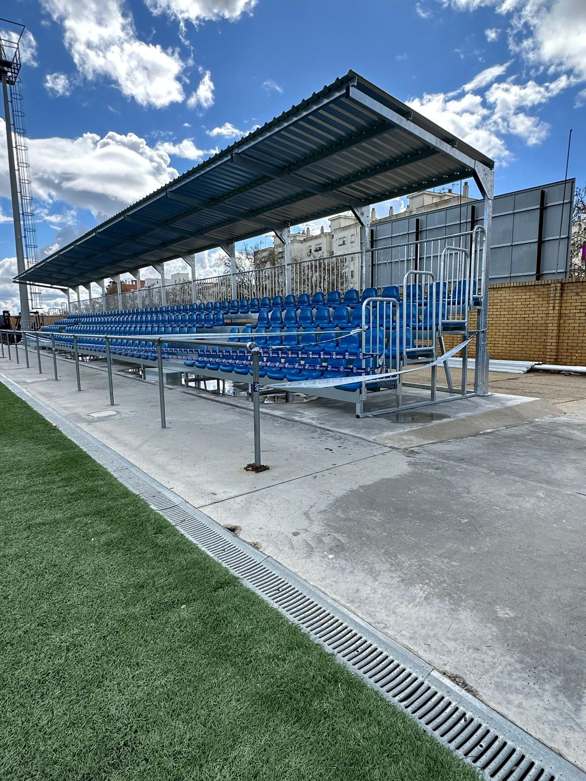 Una fila de asientos azules en un estadio con techo.