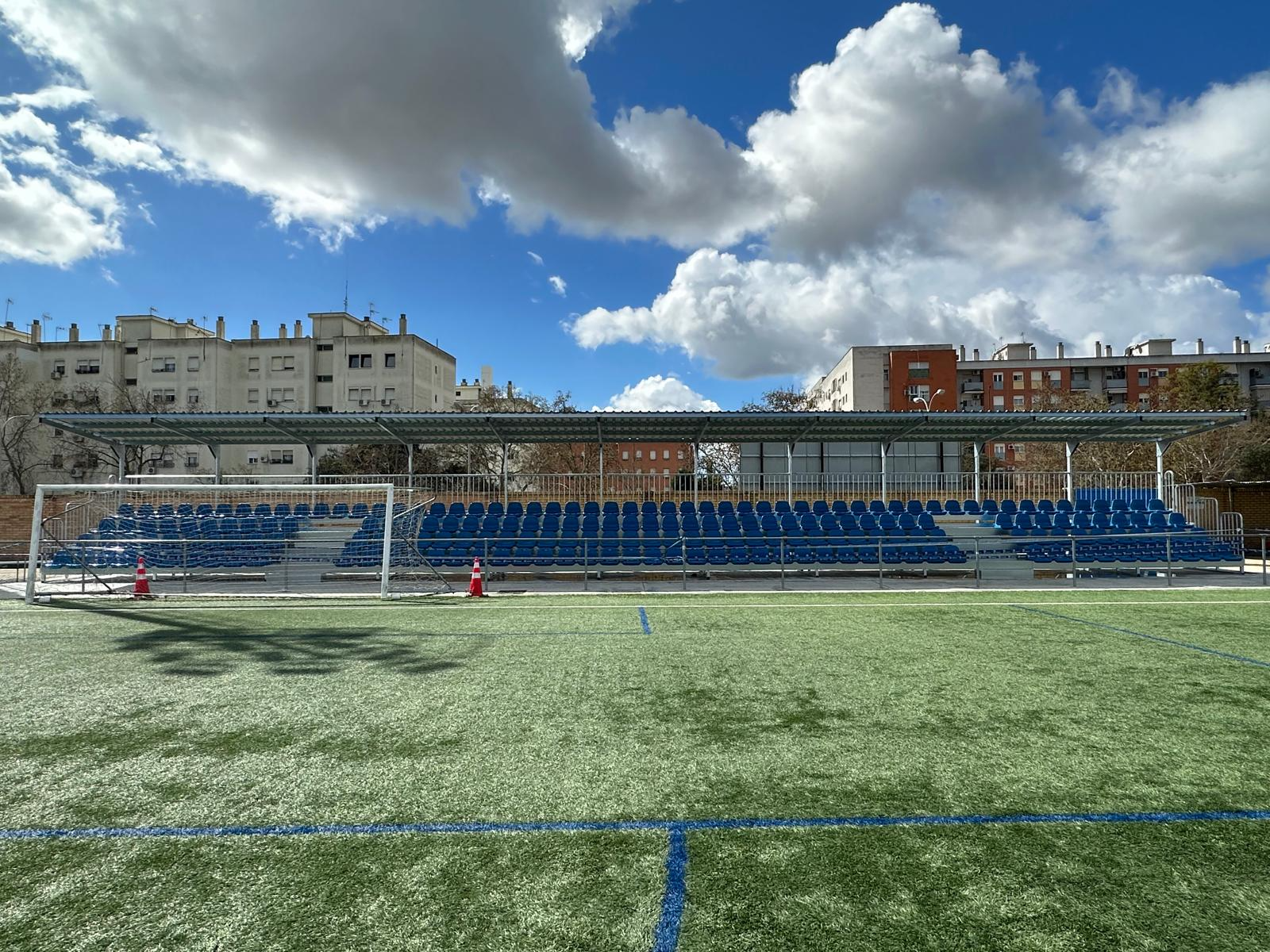 Un campo de fútbol con asientos azules y una portería.