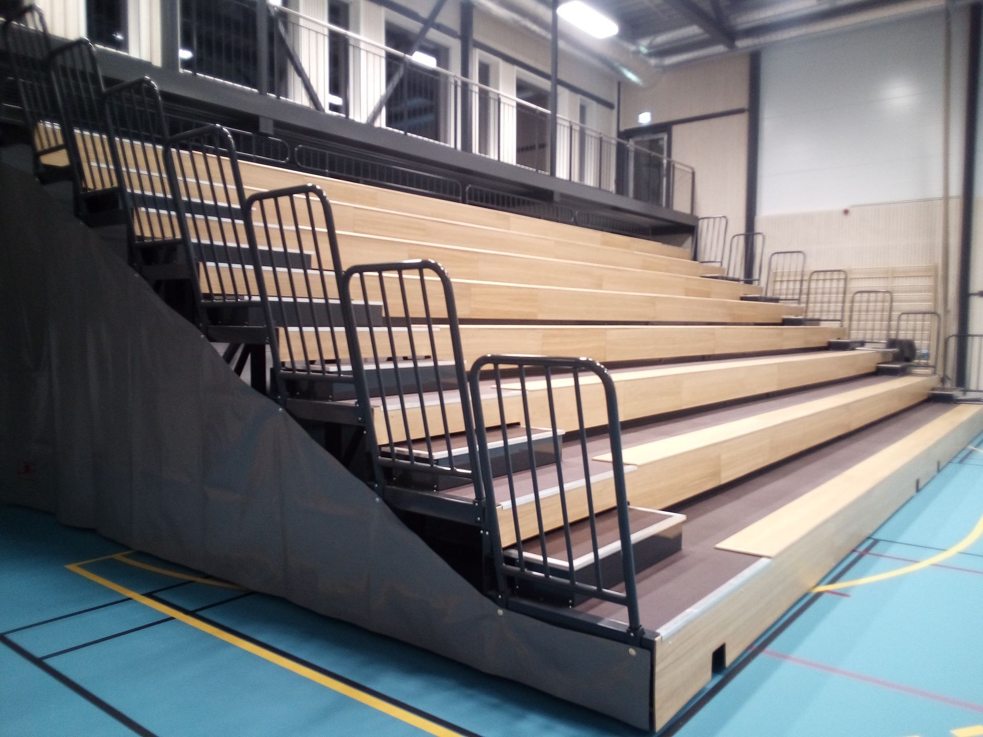 Una fila de gradas en un gimnasio con escaleras que conducen a ellas.
