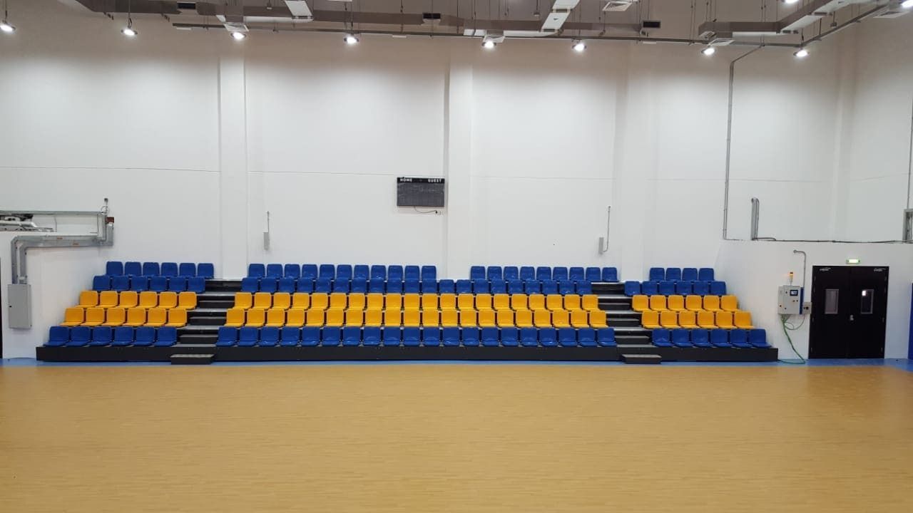 Una fila de asientos azules y amarillos en un gimnasio vacío.