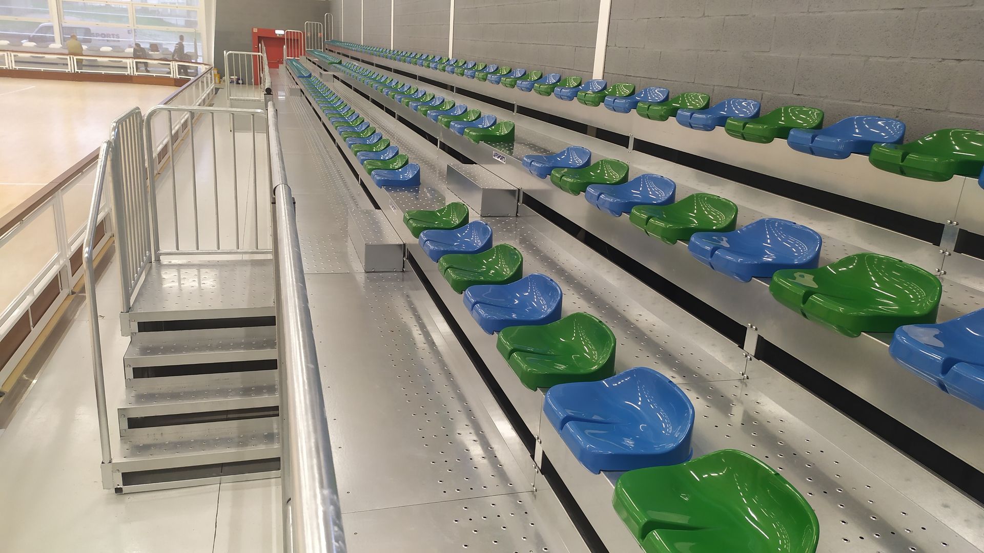 Una fila de asientos azules y verdes en un estadio