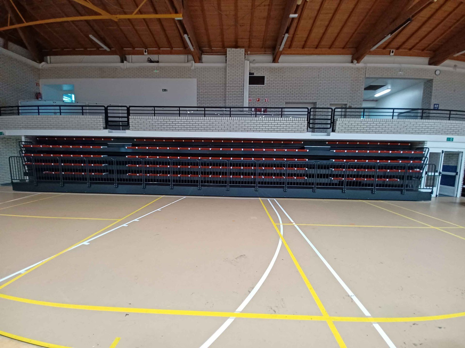 Un gimnasio vacío con gradas y una cancha de baloncesto.