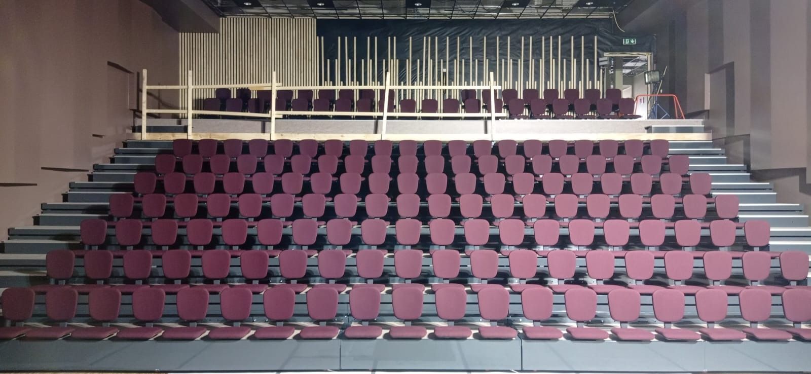 Una fila de sillas rojas están alineadas en un auditorio.