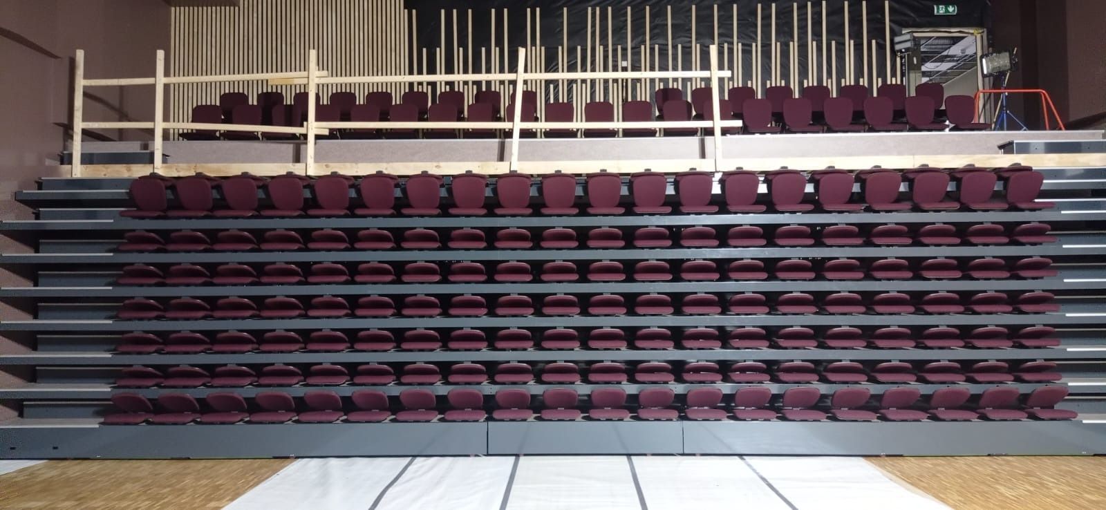 Una fila de gradas con asientos rojos y una barandilla