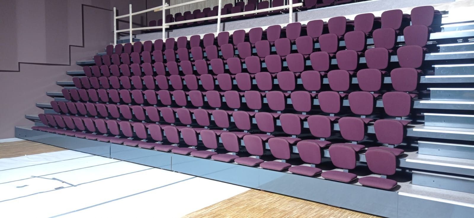 Una fila de sillas moradas están apiladas una encima de otra en un estadio.