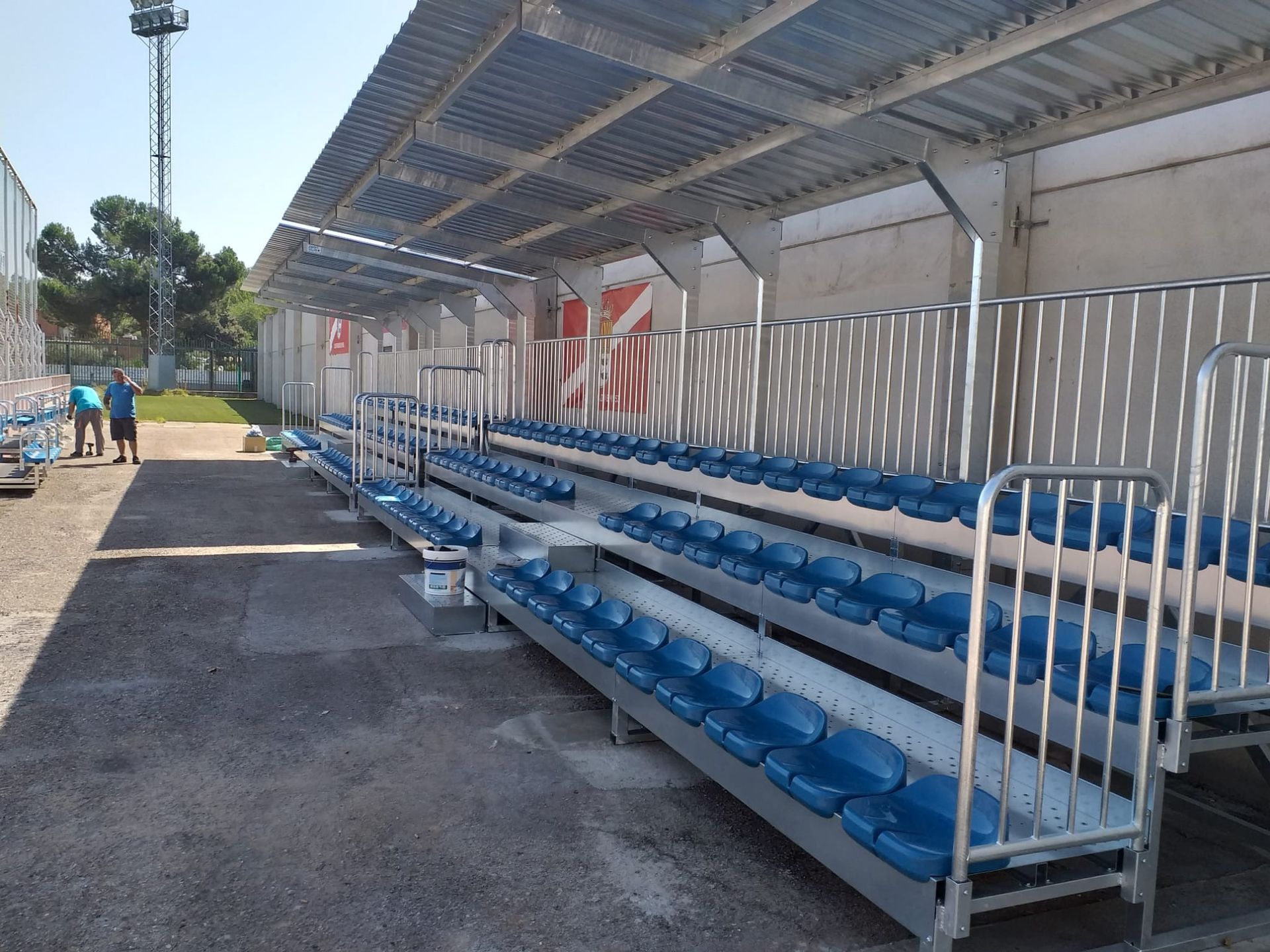 Un estadio con filas de asientos azules bajo un dosel.