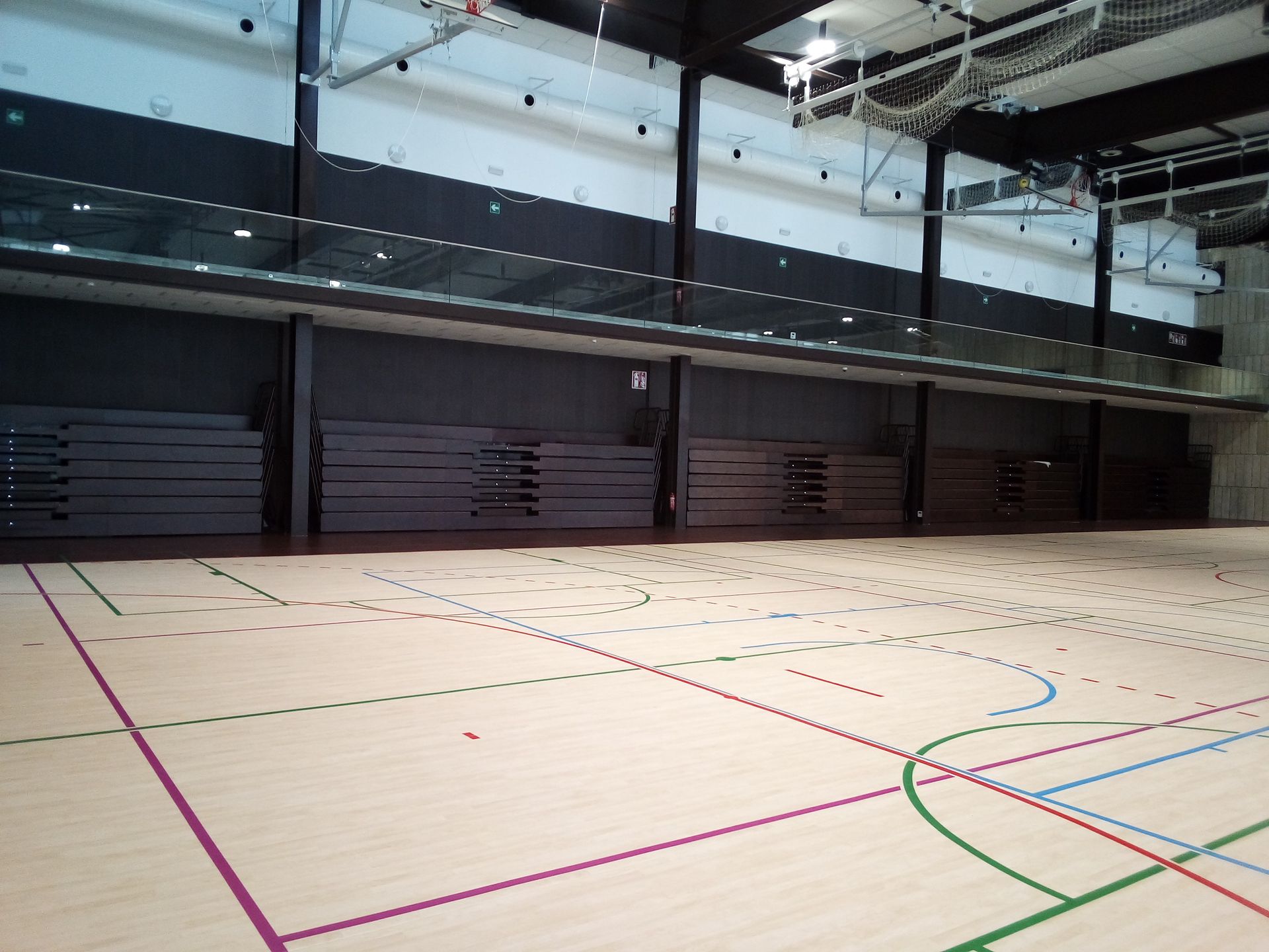Un gimnasio vacío con un aro de baloncesto al fondo.