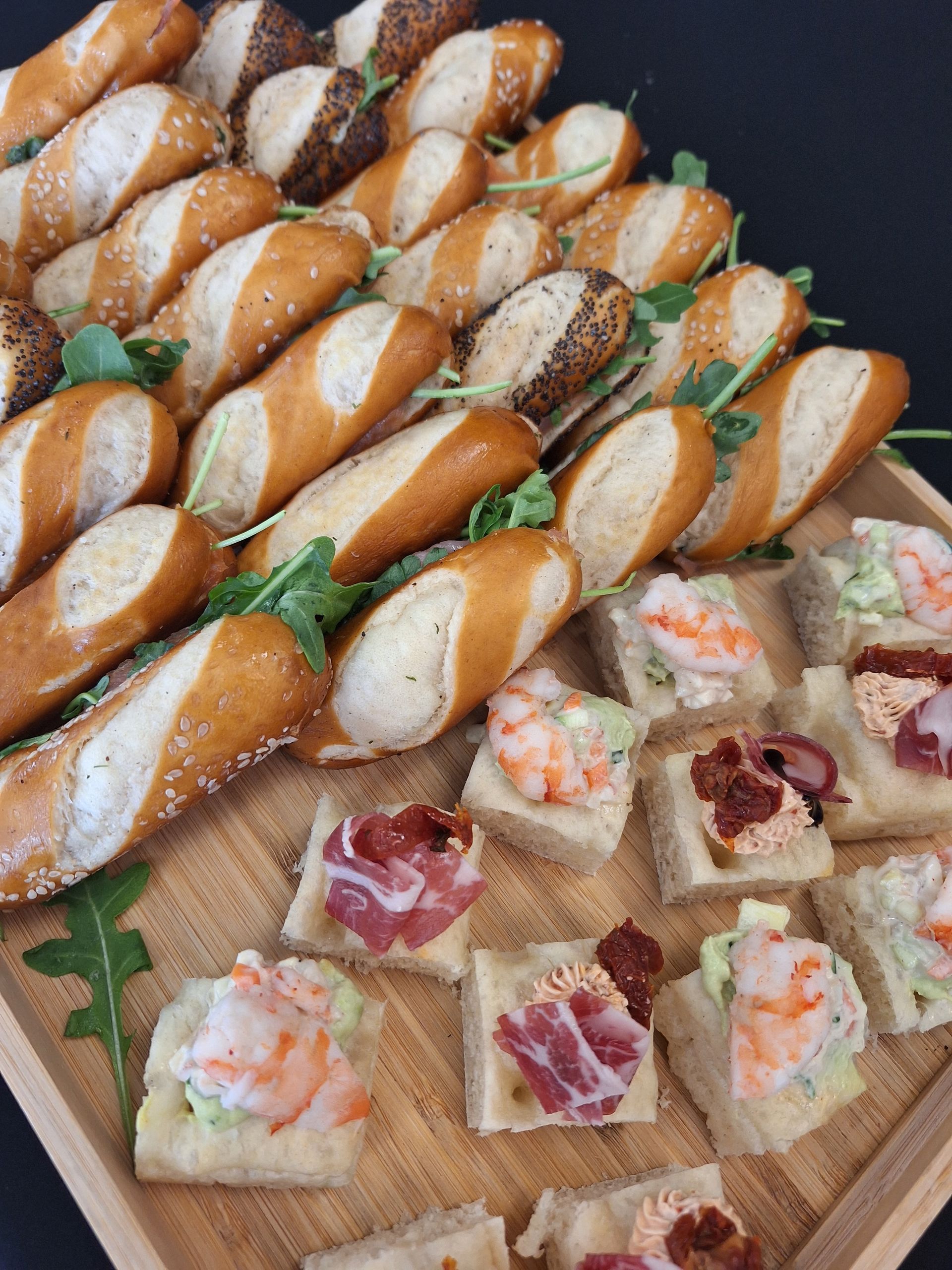 Plateau d’amuse-bouches assortis : minisandwichs sur baguette et crackers garnis de crevettes et de charcuterie.