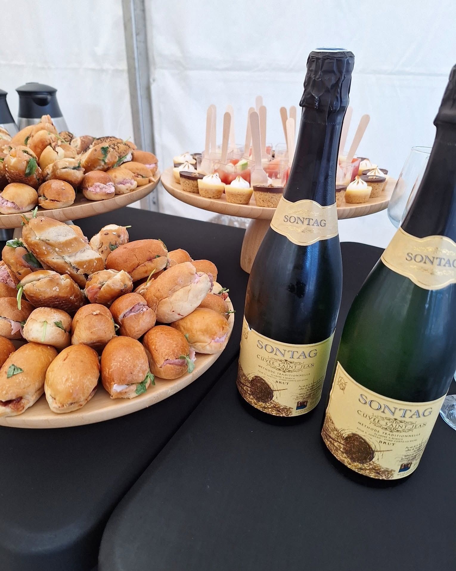 Table avec des hors-d’œuvre et deux bouteilles de vin pétillant lors d’un événement avec service traiteur