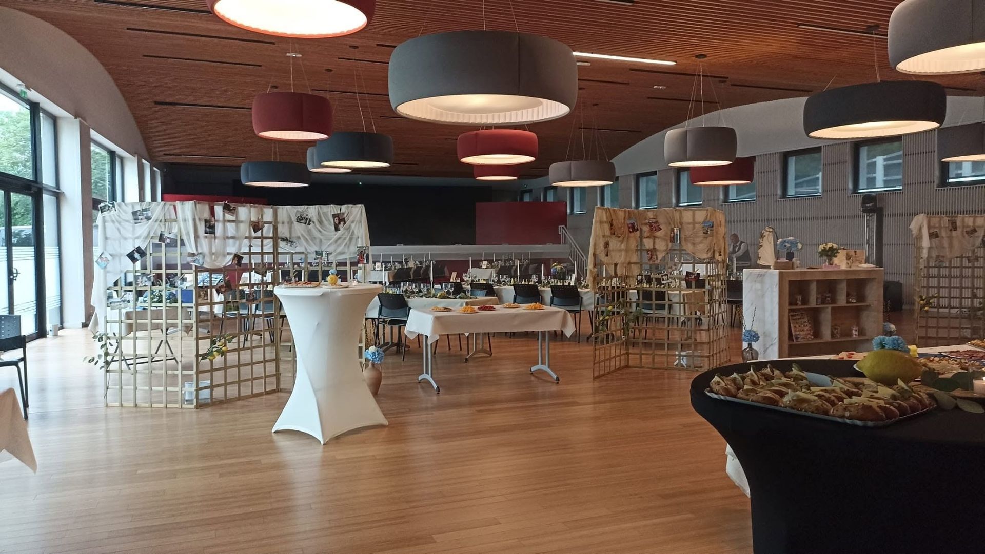 Intérieur moderne de café avec un parquet, des tables, des suspensions et un comptoir de service avec un espace pour s’asseoir.