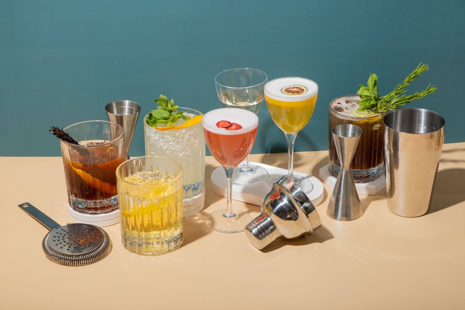 Cocktails assortis et accessoires de bar disposés sur une table devant un fond bleu