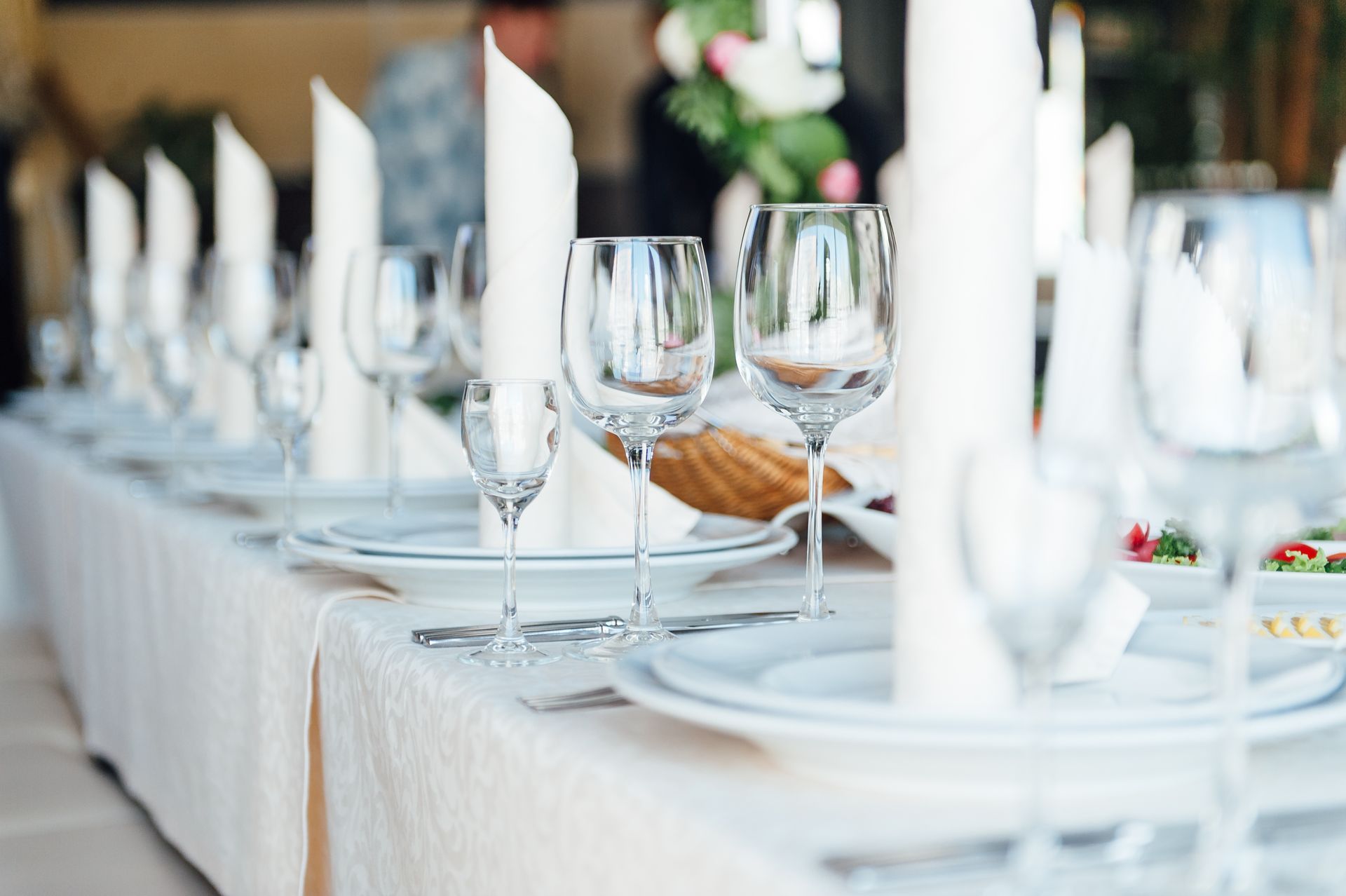 Élégante table dressée en blanc avec des verres à vin, des serviettes pliées et des assiettes lors d’un banquet officiel