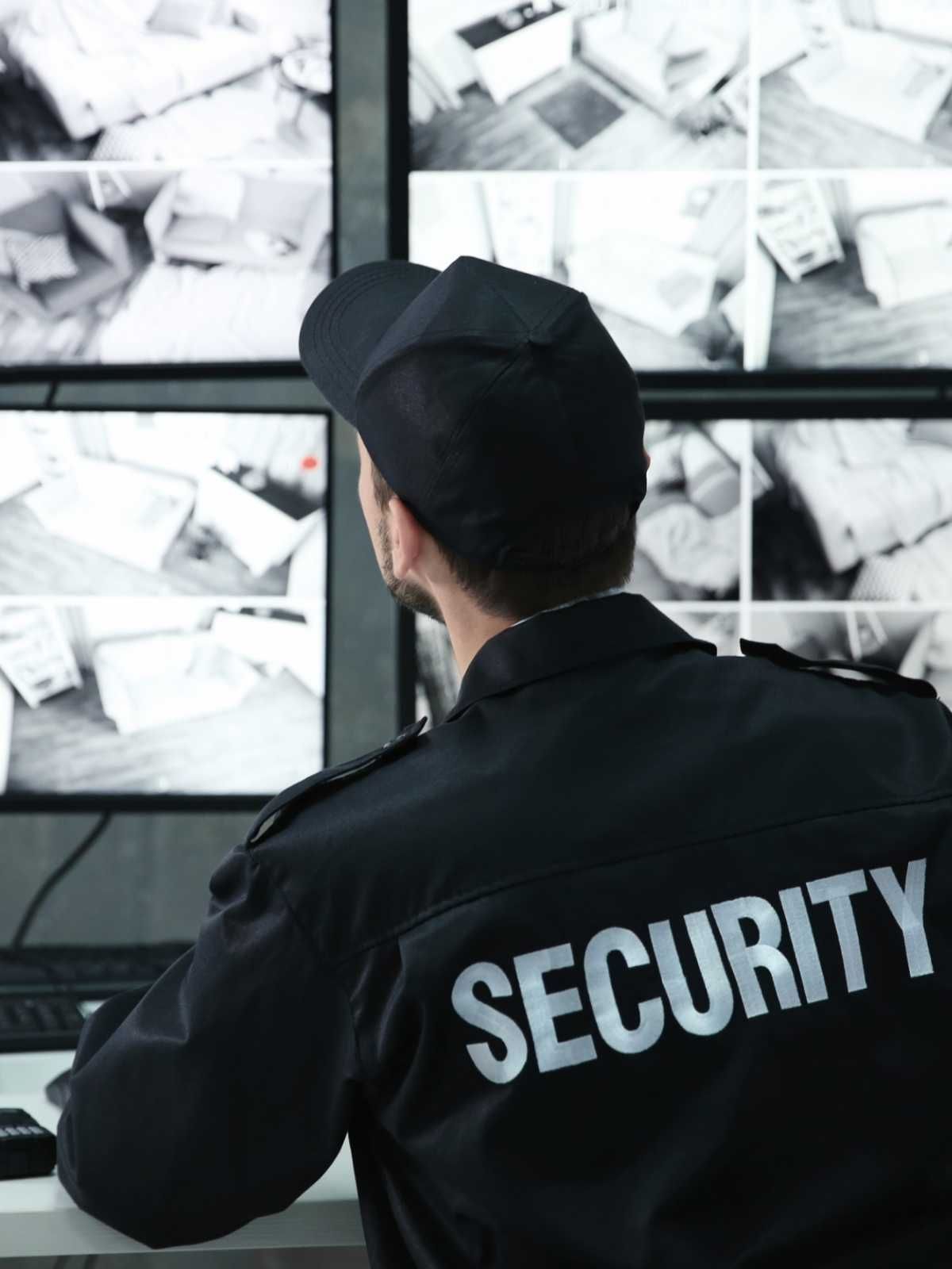 Un guardia de seguridad está sentado frente a un monitor de computadora.