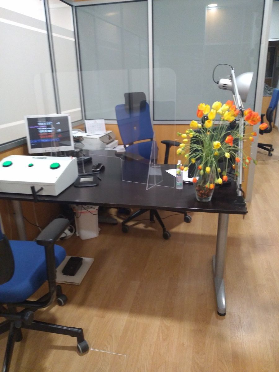 Un escritorio con una computadora portátil y un jarrón de flores encima.