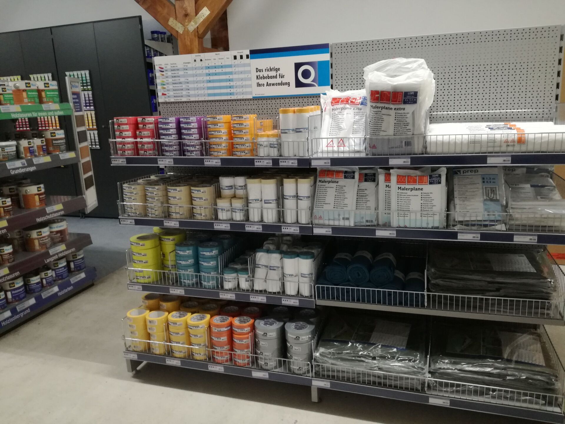 Regale in einem Laden, gefüllt mit Farbdosen, Werkzeugen und Zubehör.