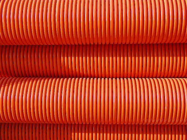 Orangefarbene, gewellte Kunststoffrohre gestapelt