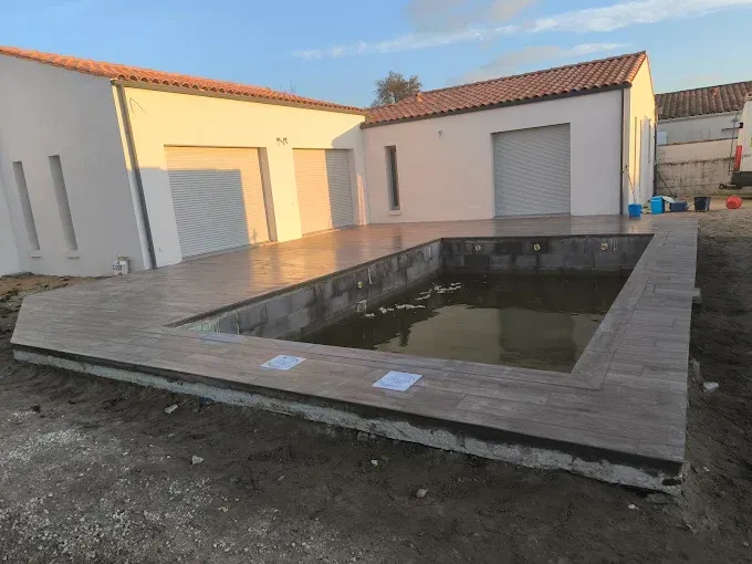 Cour arrière avec piscine creusée rectangulaire, terrasse en pierre et portes de garage en arrière-plan