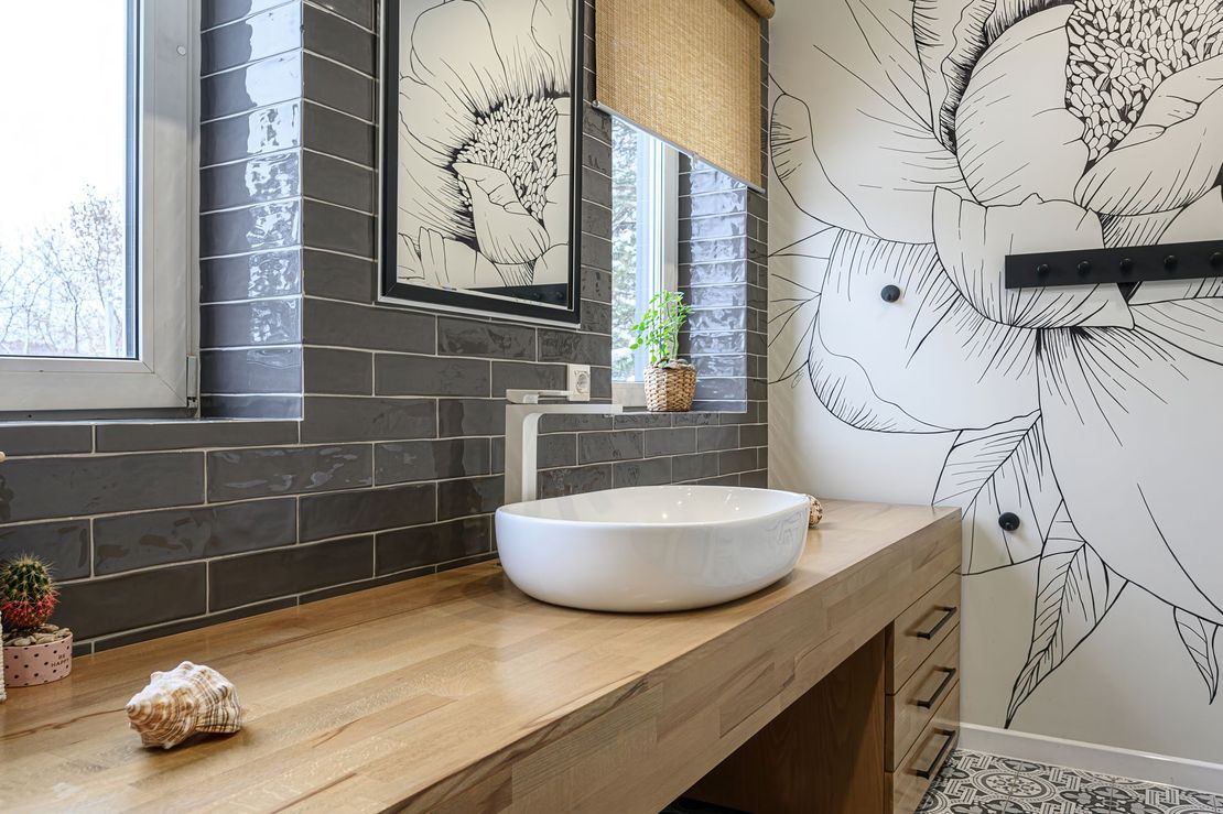 Salle de bains moderne avec meuble-lavabo en bois, vasque blanche et décoration murale à effet craquelé dans les tons gris.