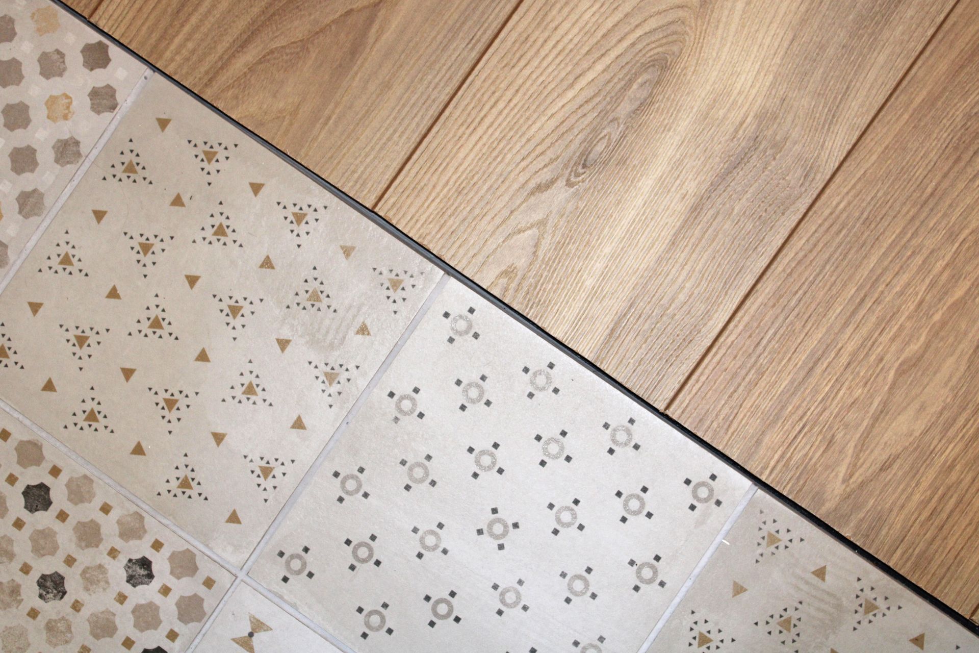 Vue en diagonale d'un parquet rencontrant un carrelage blanc à motifs
