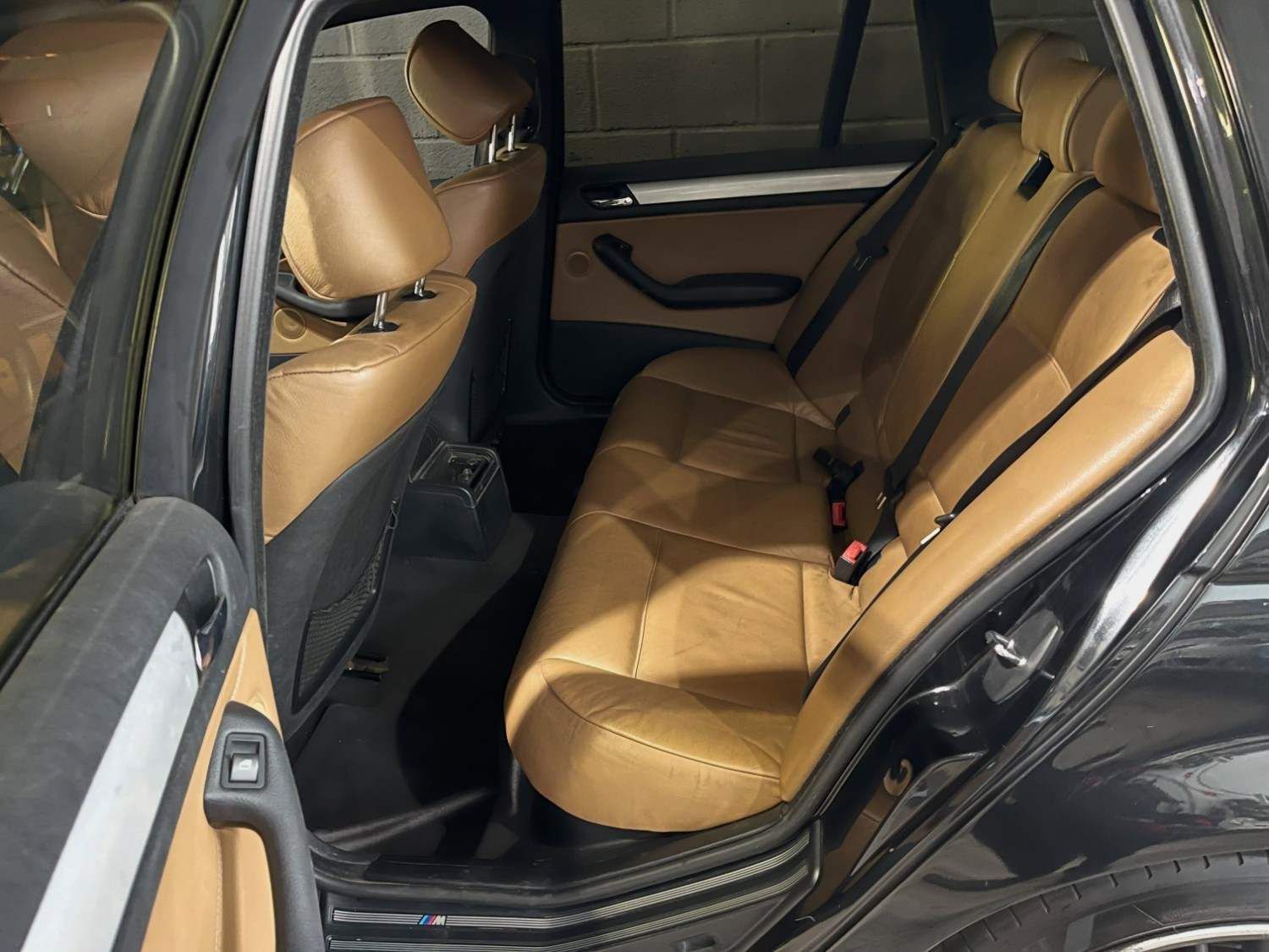 Asientos de automóvil color canela dañados dentro de un sedán negro con airbags desplegados y tapicería rasgada