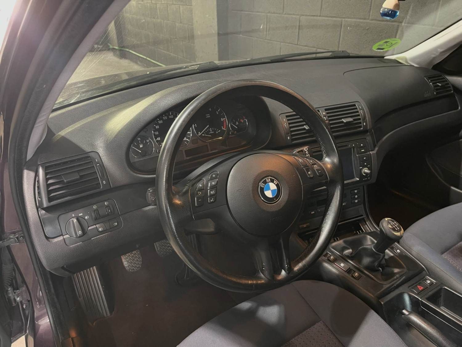 Interior de un BMW con volante de cuero negro, salpicadero y consola central, visto desde el asiento del conductor
