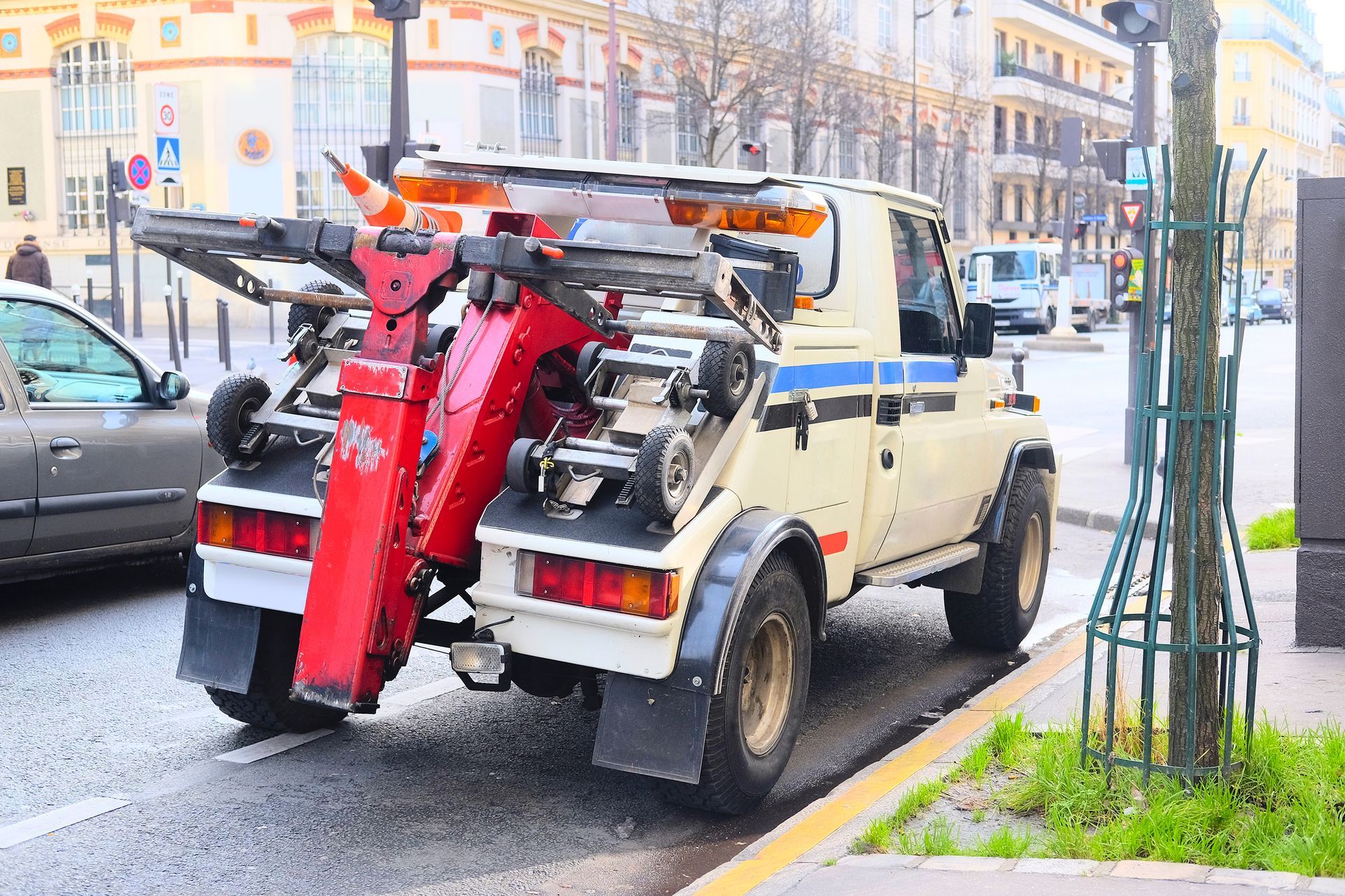 Une dépanneuse blanche avec un mécanisme de levage rouge est stationnée dans une rue de la ville.