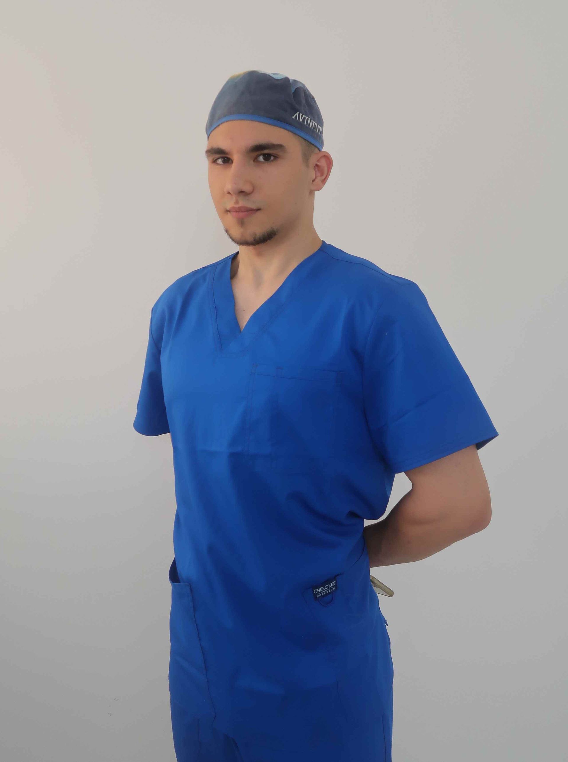 Un hombre vestido con uniforme azul y un gorro quirúrgico.