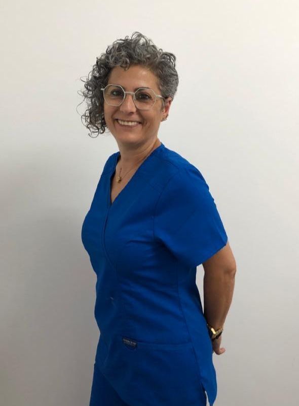 Una mujer con uniforme azul y gafas sonríe a la cámara.