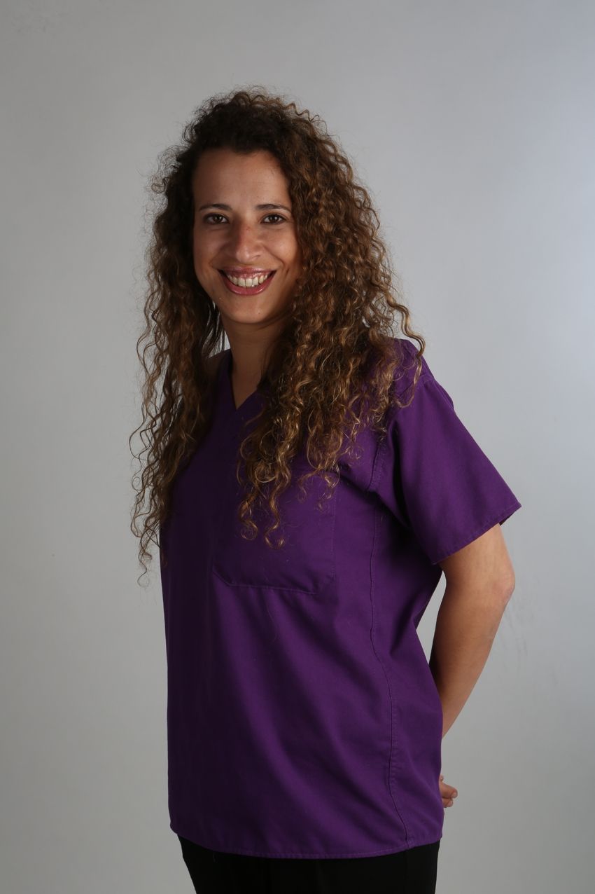 Una mujer con cabello rizado lleva una blusa morada.
