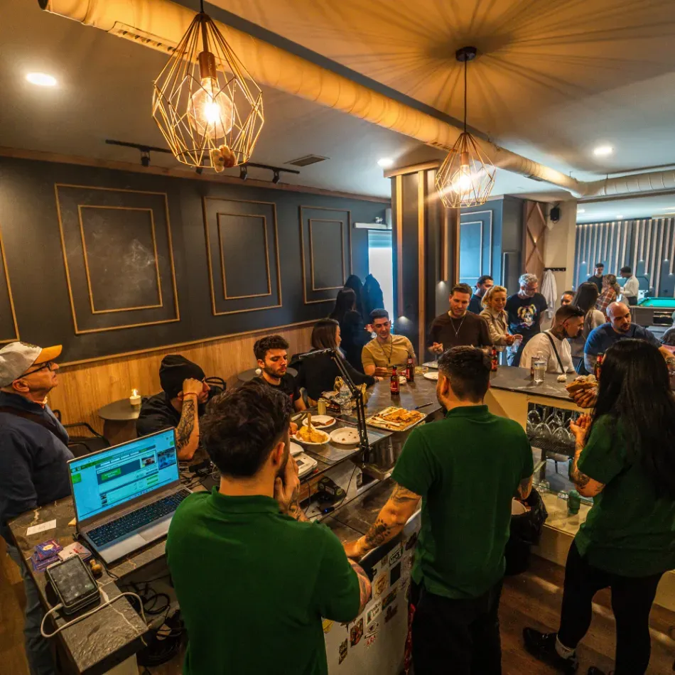 La gente se reunió en un acogedor café-bar con iluminación cálida y ordenadores portátiles sobre la barra.