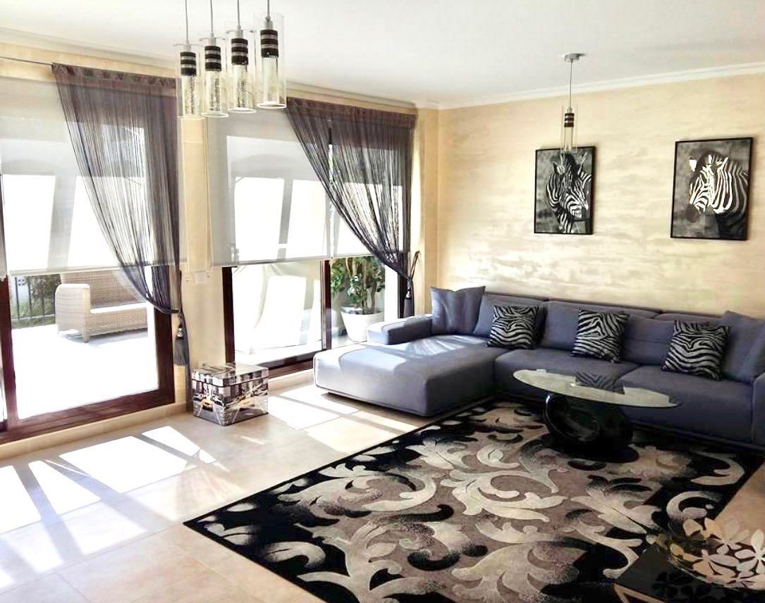 Una sala de estar con sofá, alfombra, mesa de café y puertas corredizas de vidrio.