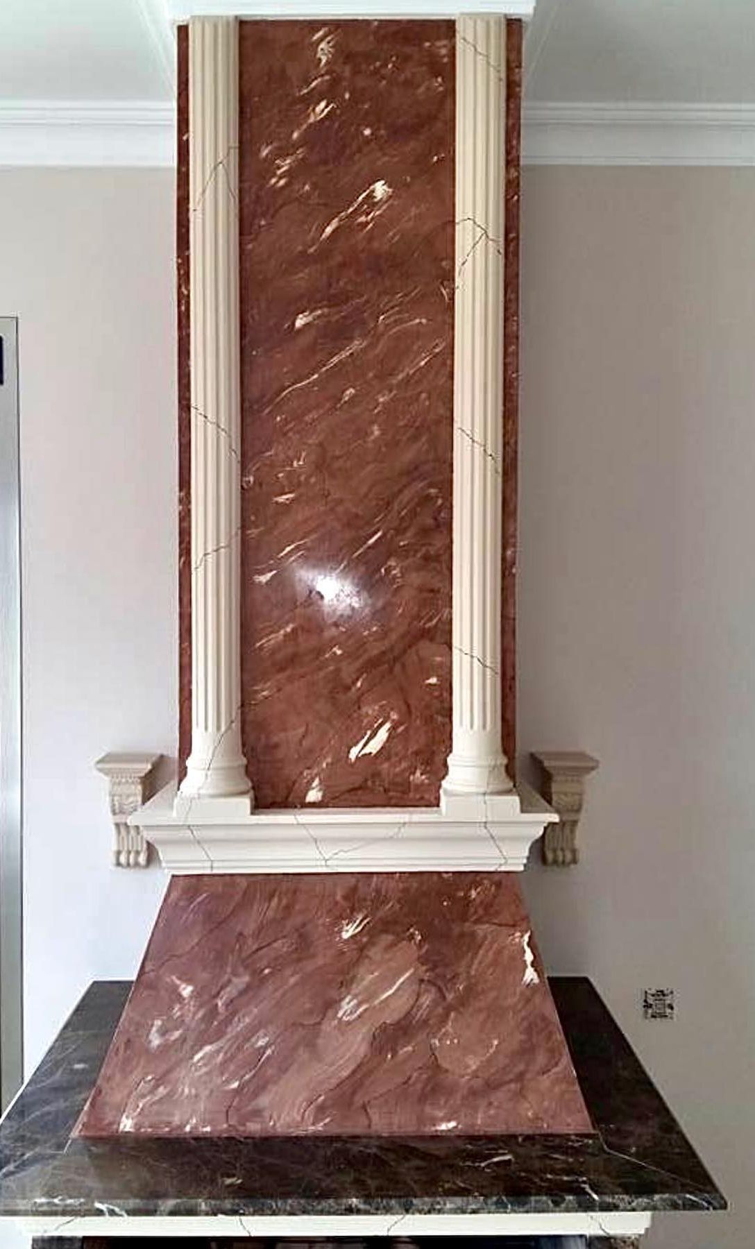 Una campana de chimenea de mármol rojo con columnas en una cocina.