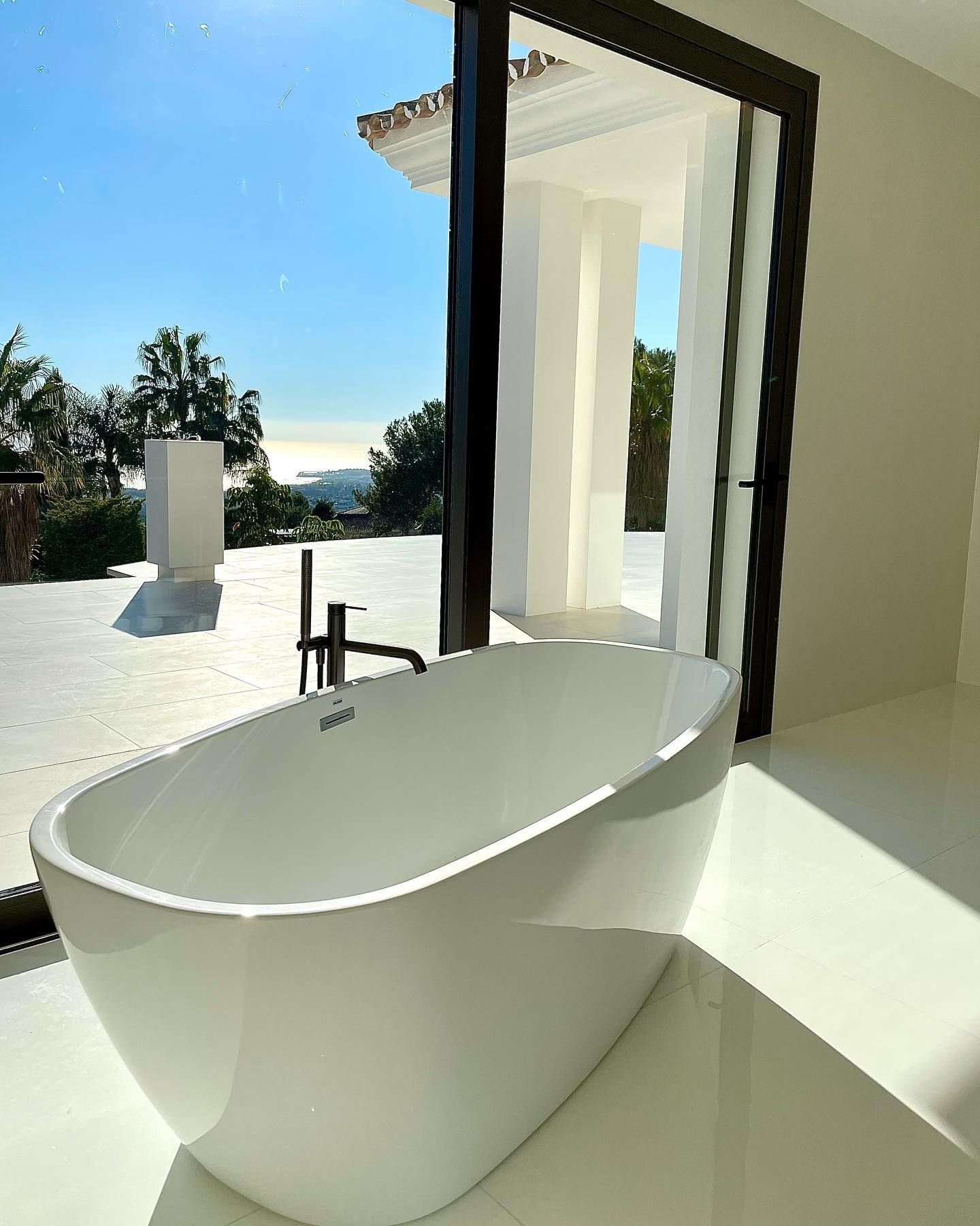 Una bañera blanca en un baño junto a una ventana.