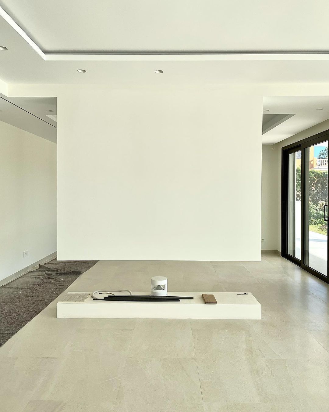 Una gran habitación vacía con una pared blanca y puertas corredizas de vidrio.