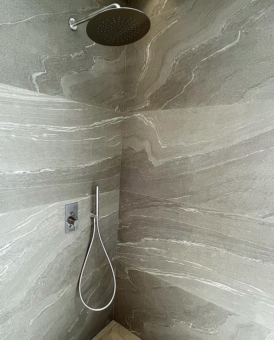 Un cabezal de ducha cuelga de la esquina de la pared del baño.