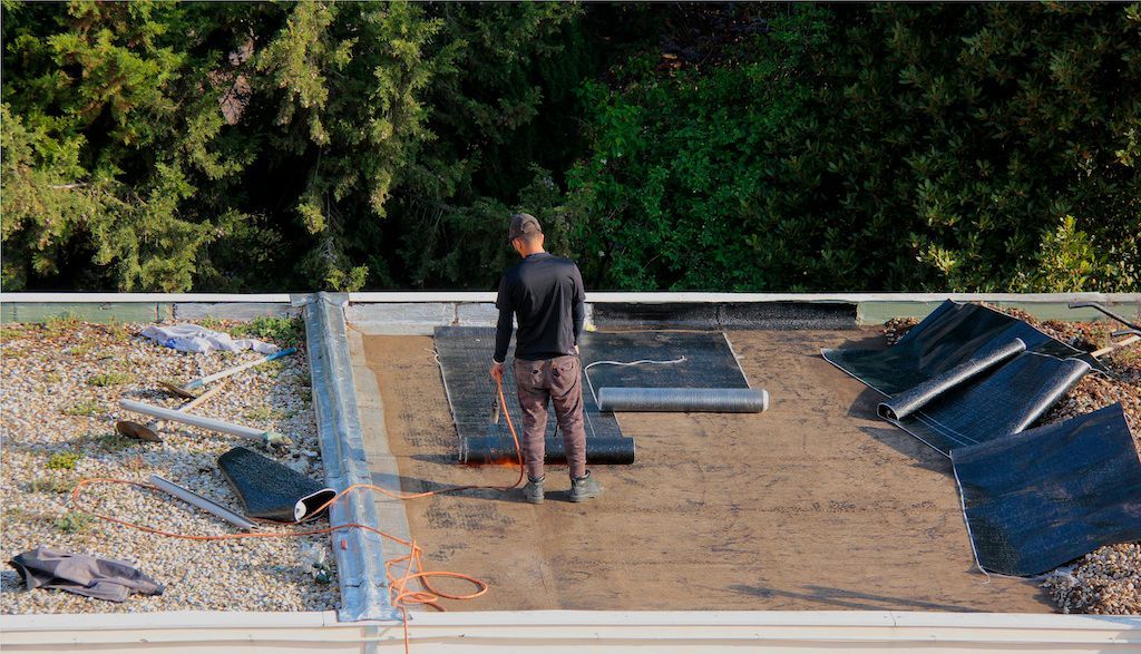 Ouvrier réalisant l'étanchéité d'un toit-terrasse