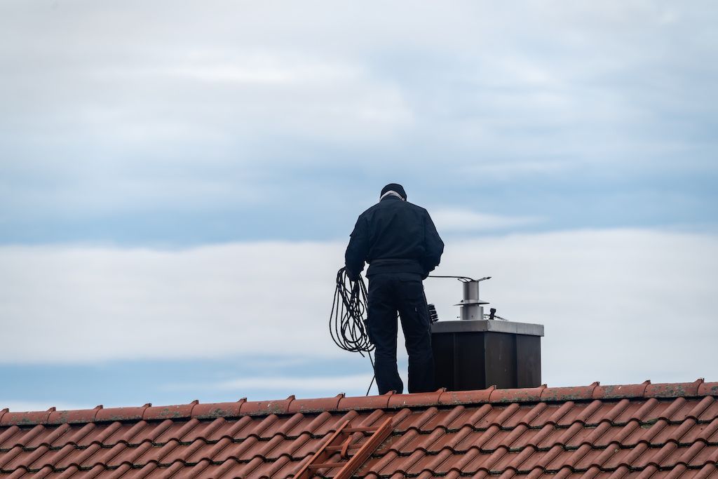 Ouvrier sur un toit procédant au ramonage d'une cheminée